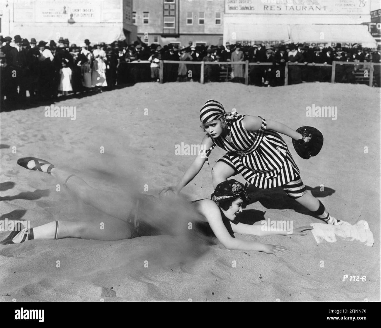 MACK SENNETT'S BATHING BEAUTIES MARY THURMAN and PHYLLIS HAVER circa 1917 playing baseball on the sand at Venice Beach California while large audience watches them during promotional appearance for Mack Sennett Comedies distributed by Paramount Pictures Stock Photo