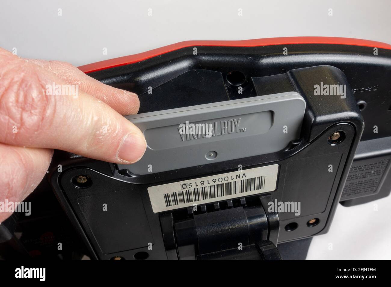 Putting a game cartridge in the slot of a Nintendo Virtual Boy table-top video game console, launched in Japan 1995, (it did not launch in Europe). Stock Photo