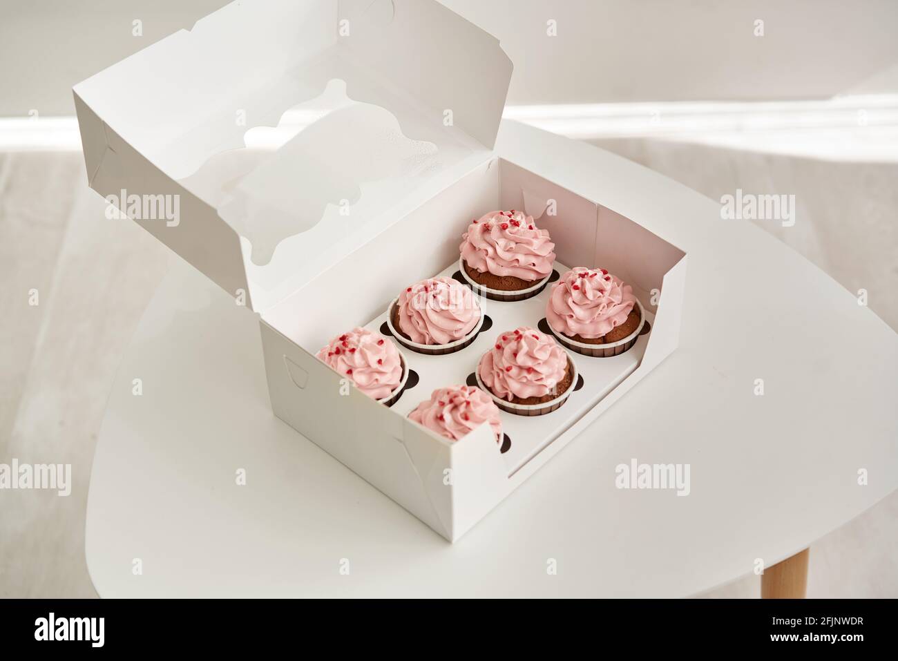 Pink cupcakes in the gift box on the white table. Stock Photo