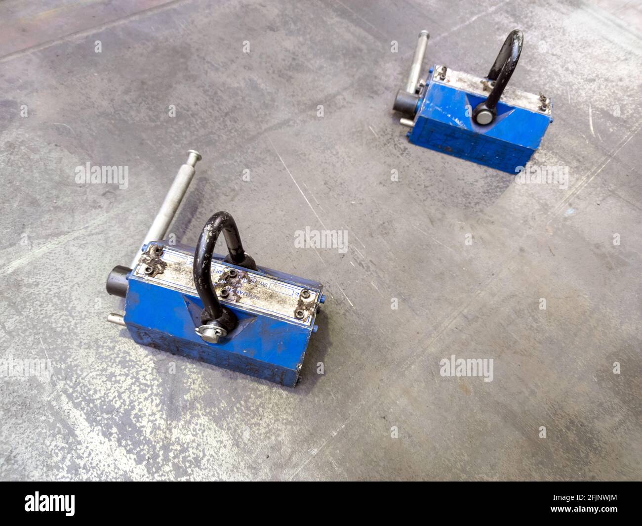 Pair of blue 600 kg industrial lifting magnets on flat sheet metal surface.  Workshop handling equipment Stock Photo - Alamy