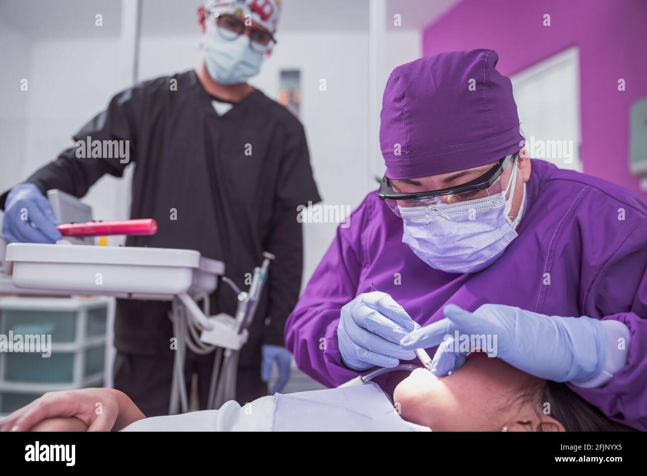 A Mexican female dentist doing dental treatment on a young girl while
