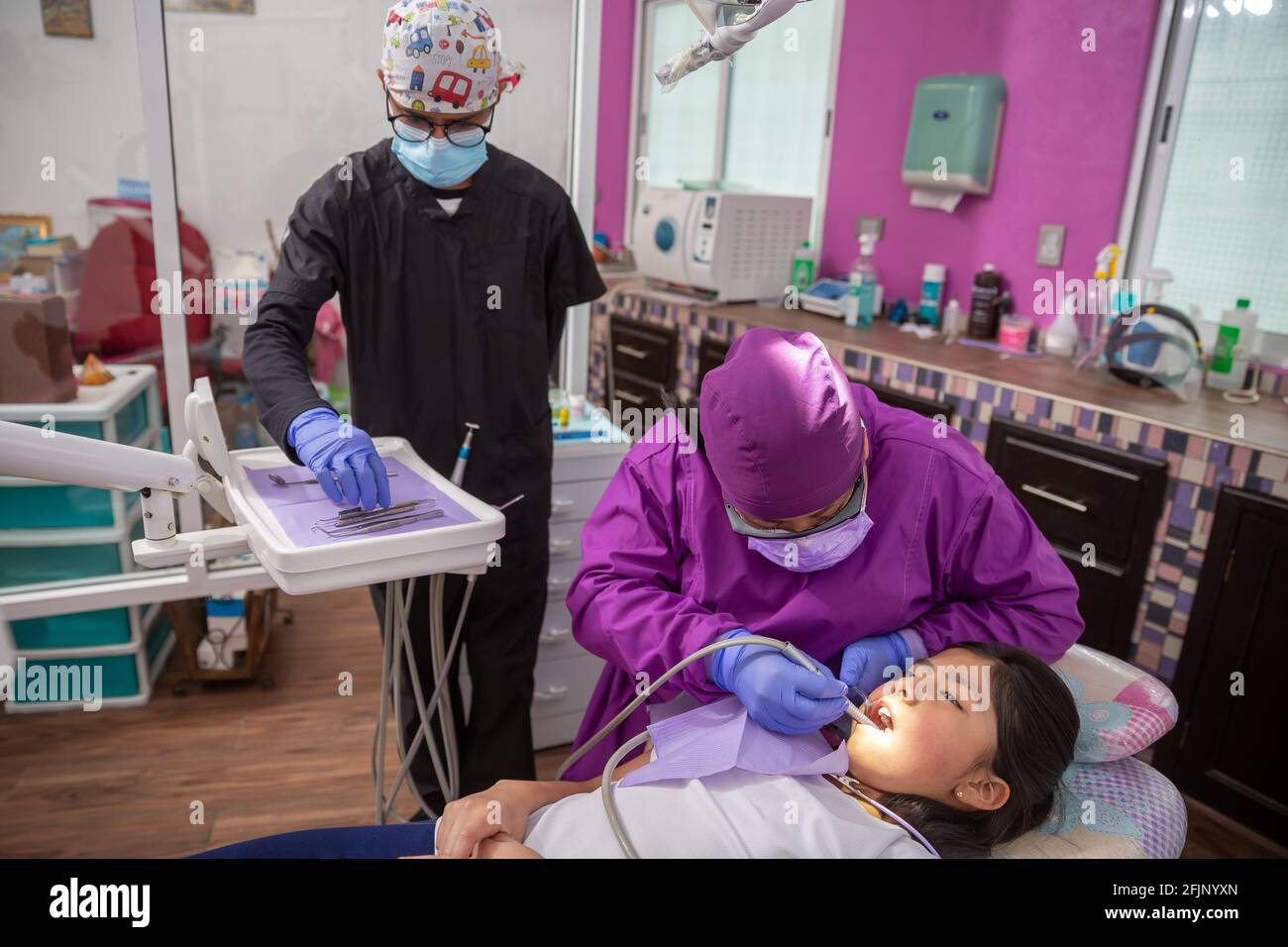 A Mexican female dentist doing dental treatment on a young girl with