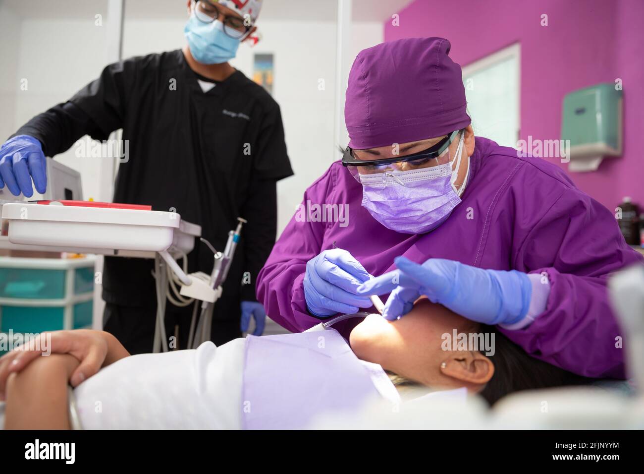 A Mexican female dentist doing dental treatment on a young girl with