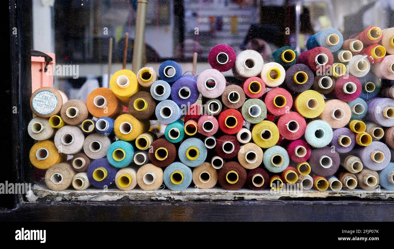 Colored  coloured cotton bobbins through glass window with black window frame Stock Photo