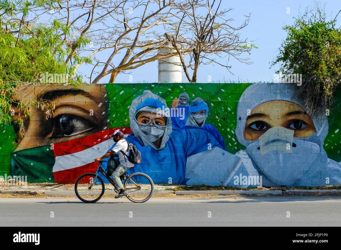 Cyclist passing in front of a mural portraying the Covid-19 first responders hailed as heroes in the fight against the pandemic , Merida Mexico Stock Photo