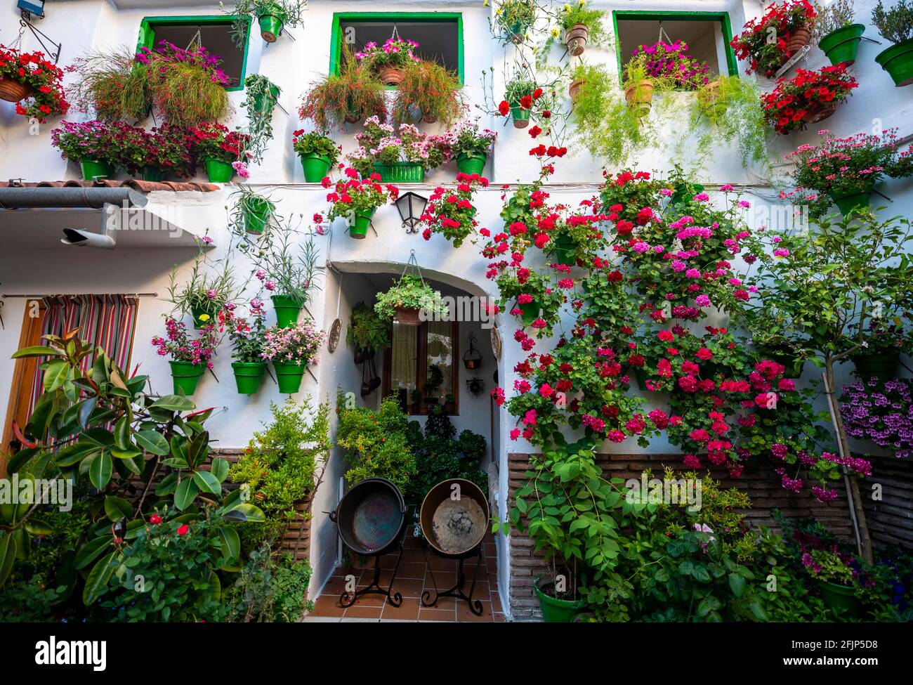 Patio decorated with flowers, geraniums in flower pots on the wall of the house with windows, Fiesta de los Patios, Cordoba, Andalusia, Spain Stock Photo