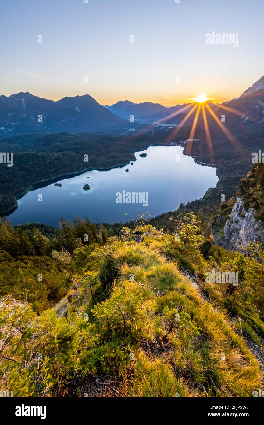 Eibsee lake at sunrise, sun shining over Bavarian alpine foothills, right Zugspitze, Wetterstein mountains near Grainau, Upper Bavaria, Bavaria Stock Photo
