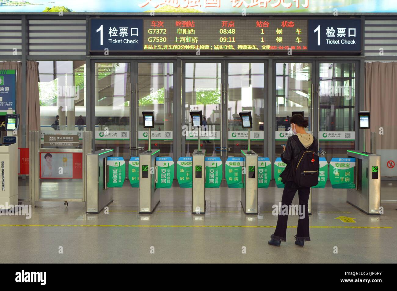 A single woman waits for her train to arrive in Jiaxing,China, when it does she can scan her ID card to go through the turnstile to the platform. Stock Photo