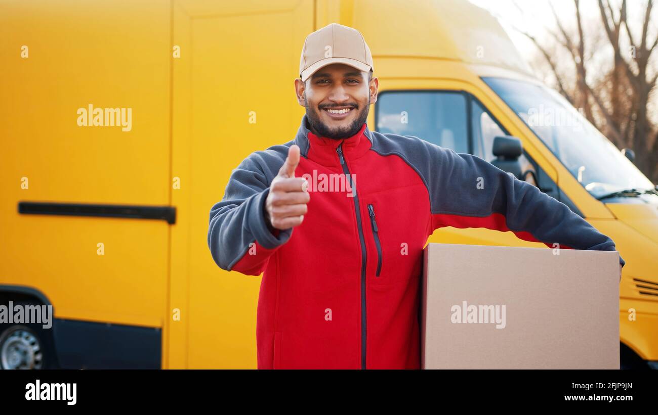 Smiling delivery man showing thumb up and looking at camera. High quality photo Stock Photo
