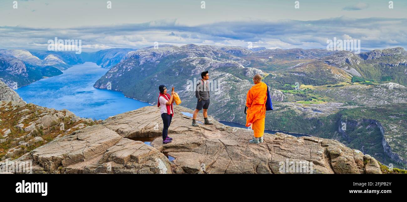 Monk among tourists at Preikestolen ( The Pulpit Rock ) at Lysefjord in Norway. Ein Mönch mit Touristen auf dem Preikestolen am Lysefjord in Norwegen. Stock Photo