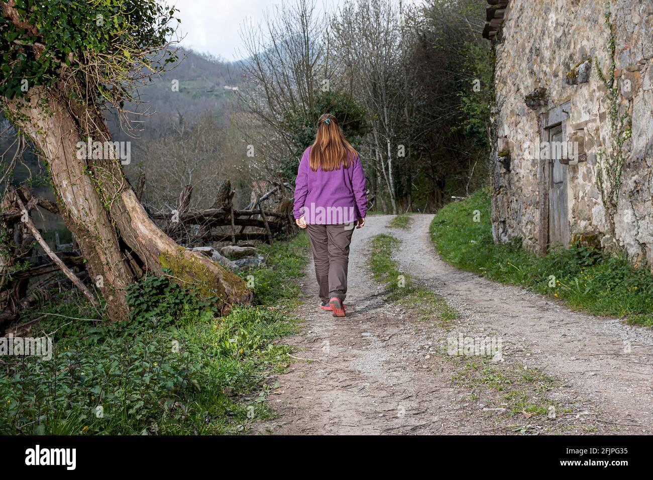 Girl walking on a path located in a council of Asturias, Spain.The photograph is taken on a cloudy day and is made in Horizontal format. Stock Photo