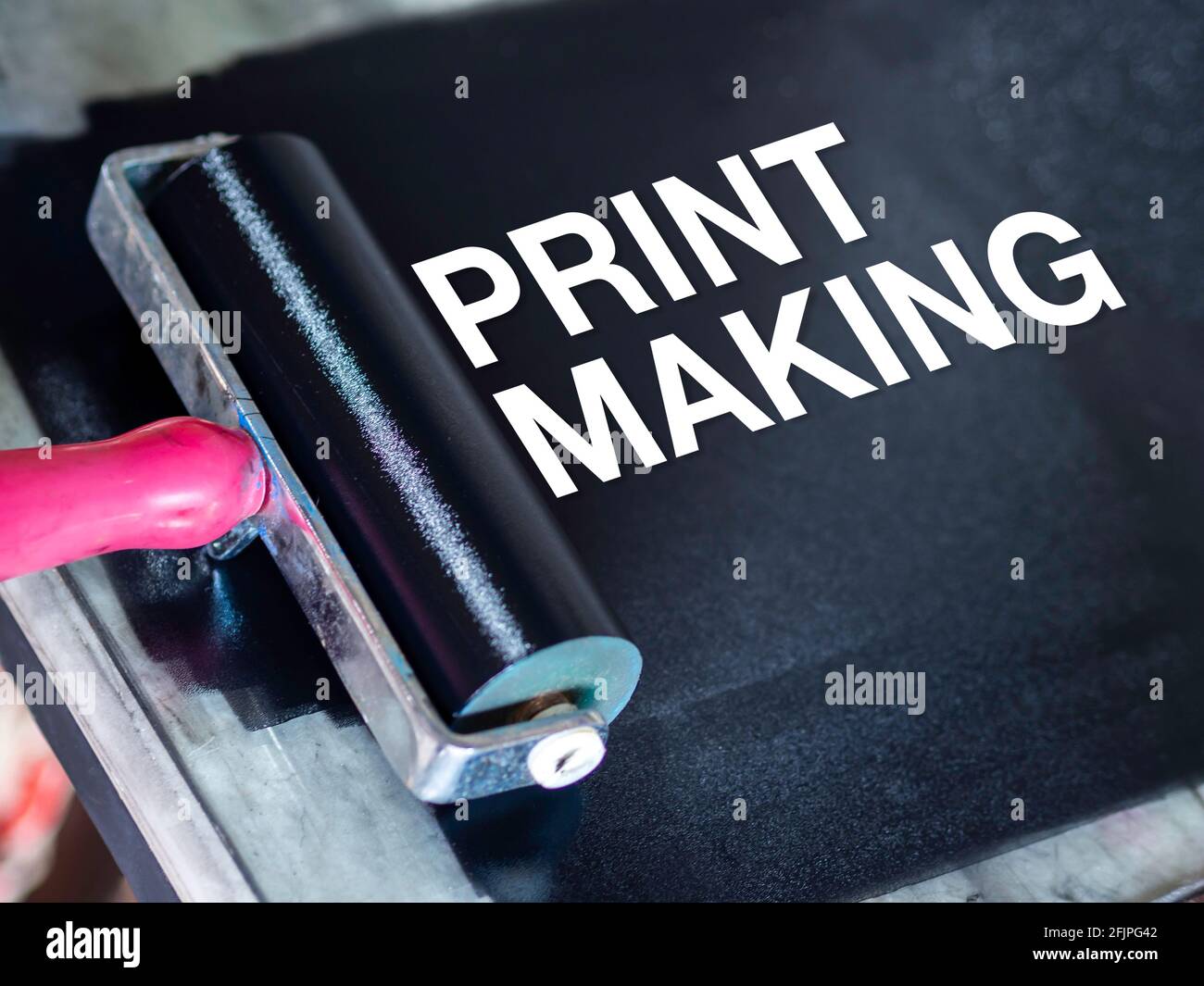 White word "printmaking" on black relief ink color on the glass with