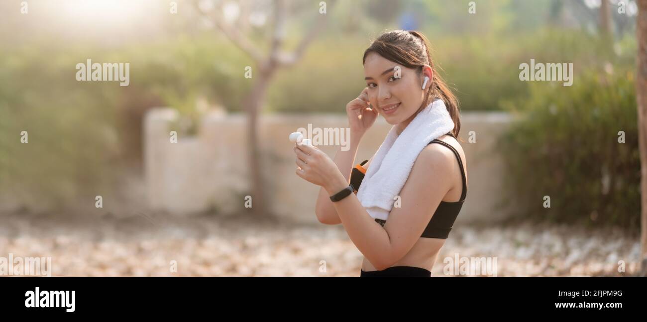 Photo of a beautiful asian young fitness woman running outdoors listening music with earphones Stock Photo