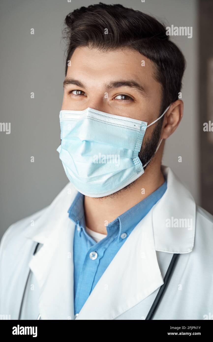 Portrait of caucasian young doctor with friendly smiling face in protective mask Stock Photo