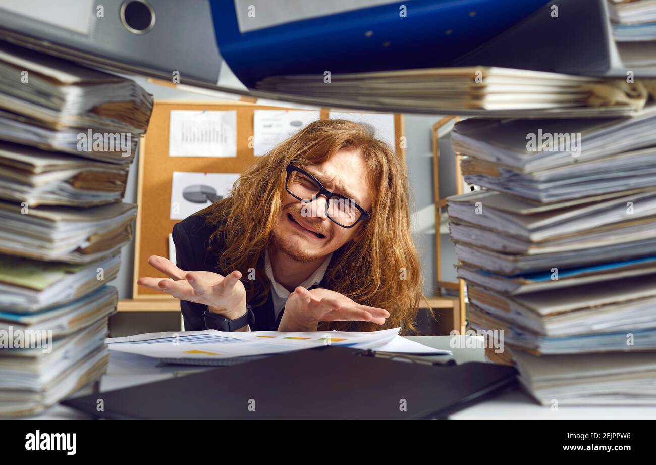 Accountant sitting at office table and crying stressed by crazy amount of paperwork Stock Photo