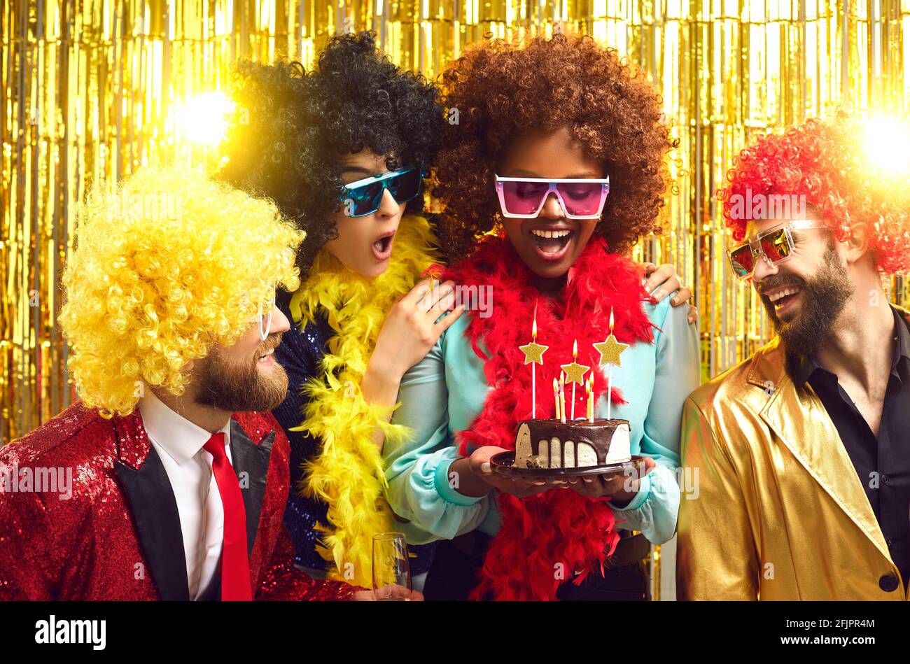 Happy multiracial people in party wigs and bra presenting cake to