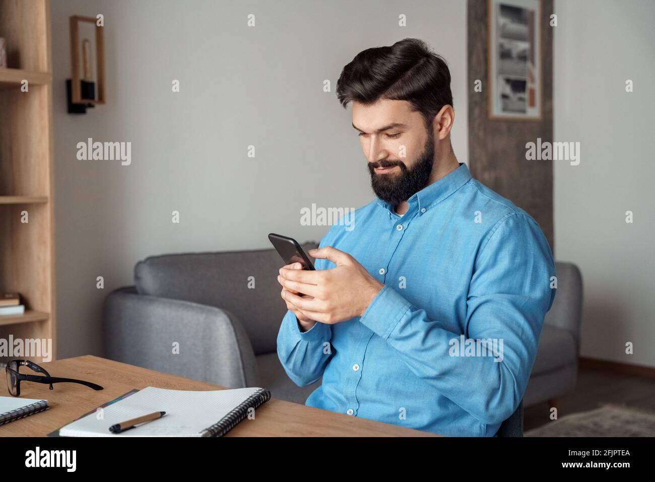 Millennial freelance businessman take break during workday using mobile phone Stock Photo
