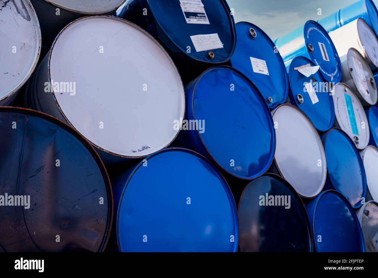 Closeup old chemical barrels. Blue and white oil drum. Steel oil tank. Toxic waste warehouse. Hazard chemical barrel. Industrial waste in old drum. Stock Photo