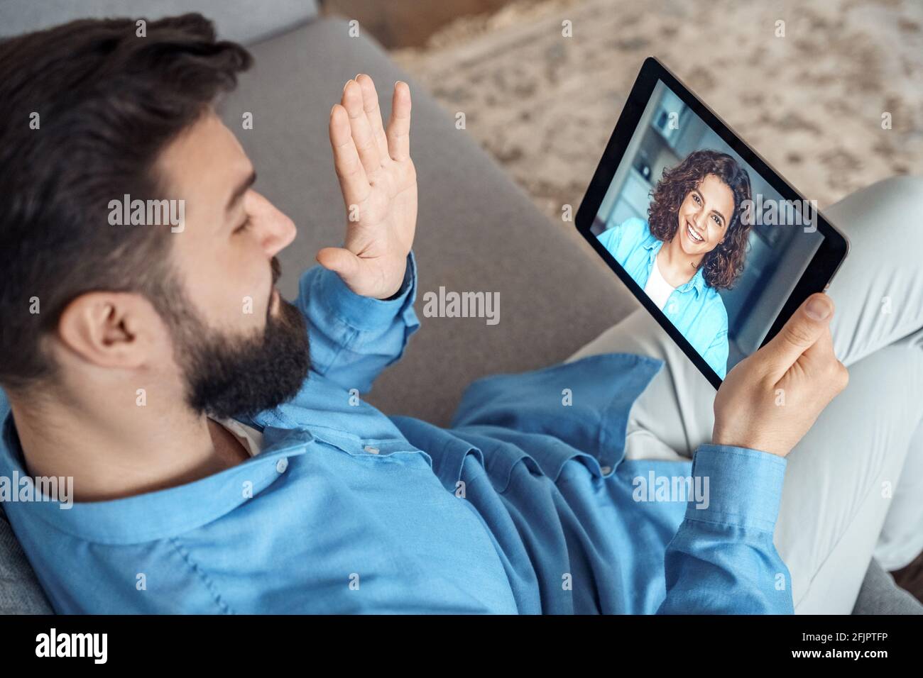 Young man holding tablet in hands having video call chat with female friend Stock Photo