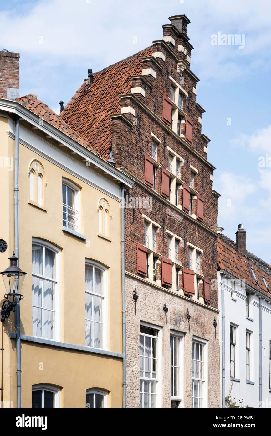 Colorful façades of historic yellow, red and white houses in Deventer. The middle brick house has a beautiful triangular stepped gable Stock Photo