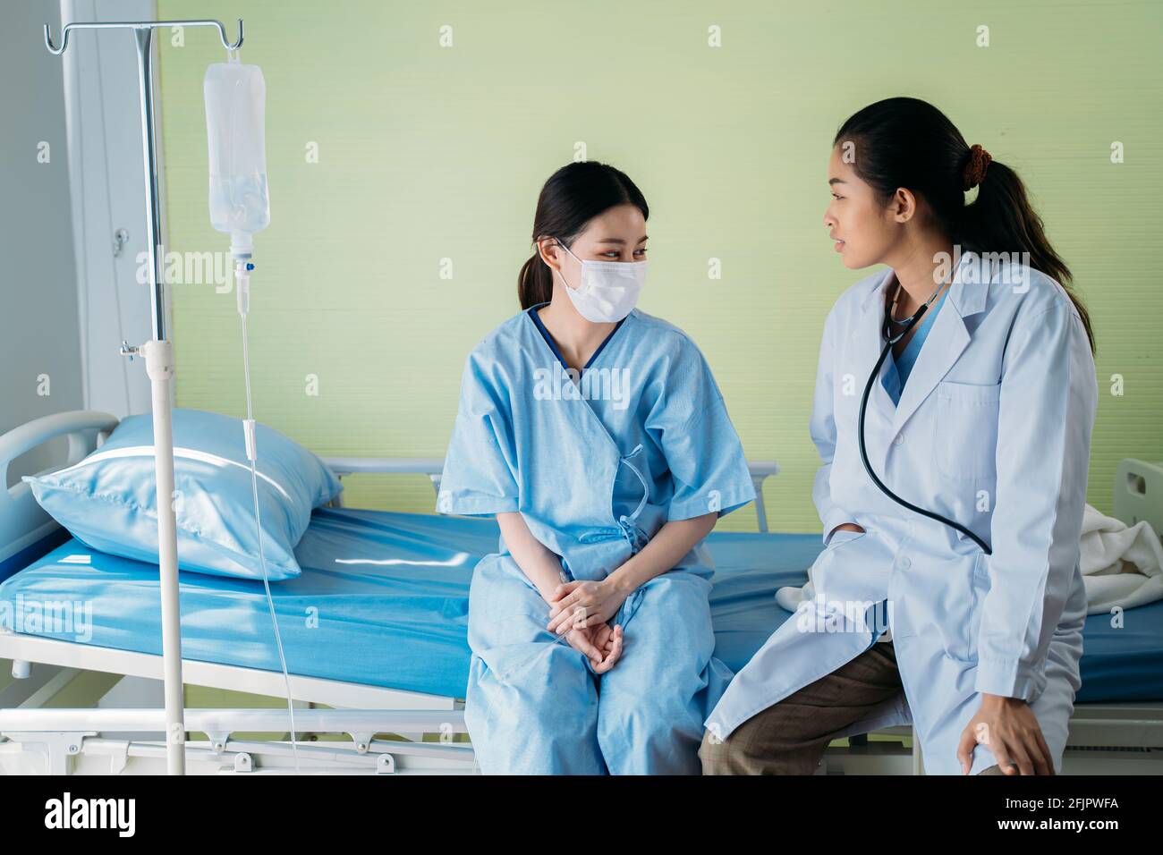 Young Asian female doctor with patient wearing surgical face mask