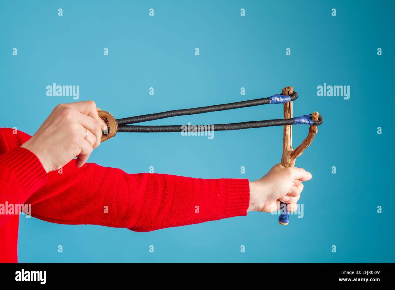 Hands of an adult man who holds a huge homemade slingshot ready to shoot Stock Photo