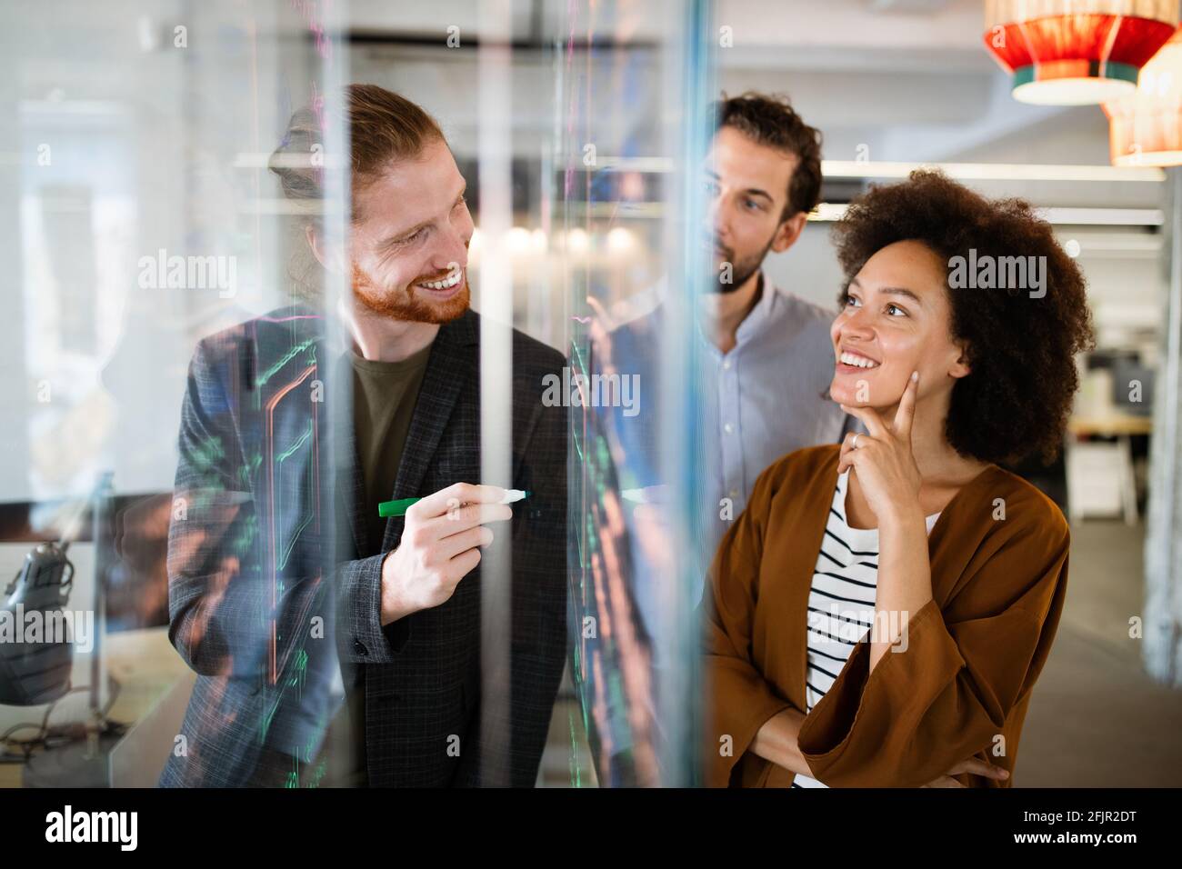 Working together on project. Happy young business colleagues working in ...