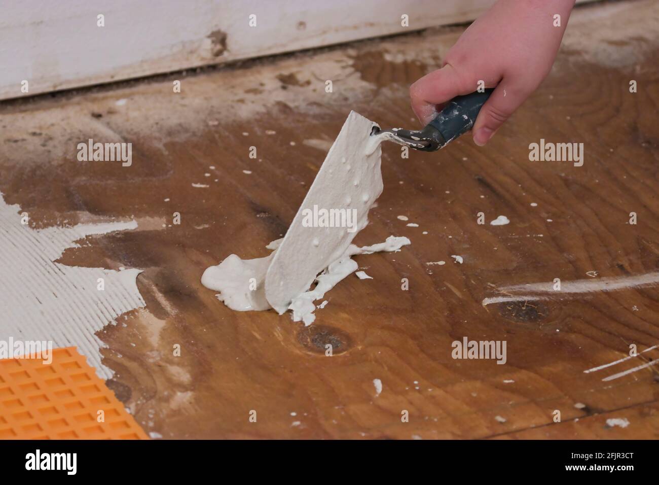 using a angled trowel to dollop cement on subflooring Stock Photo