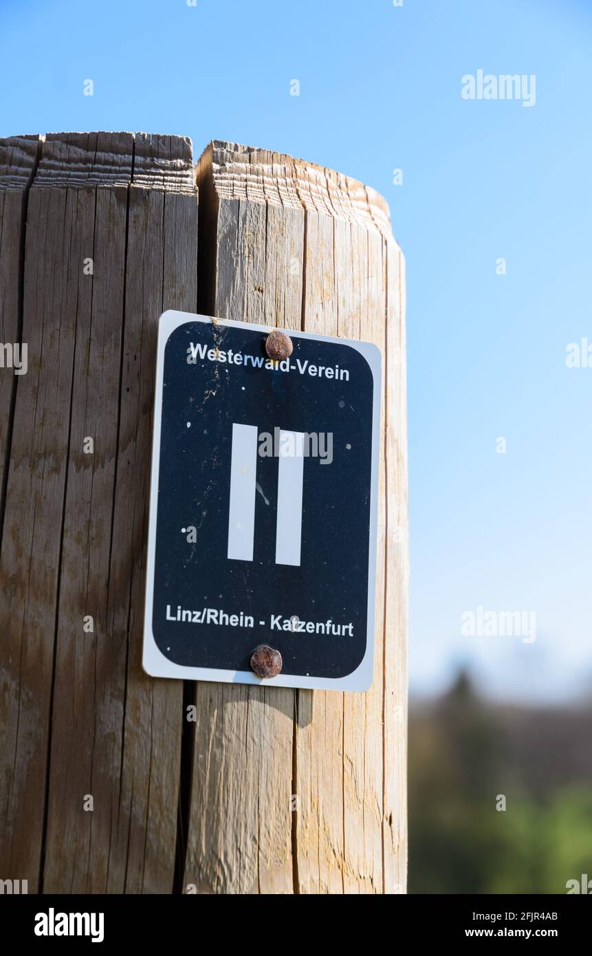 Wooden pole with waypoint or direction sign, Westerwald-Verein, Linz Rhein, Katzenfurt, along a hiking path against blue sky in Germany, Europe Stock Photo