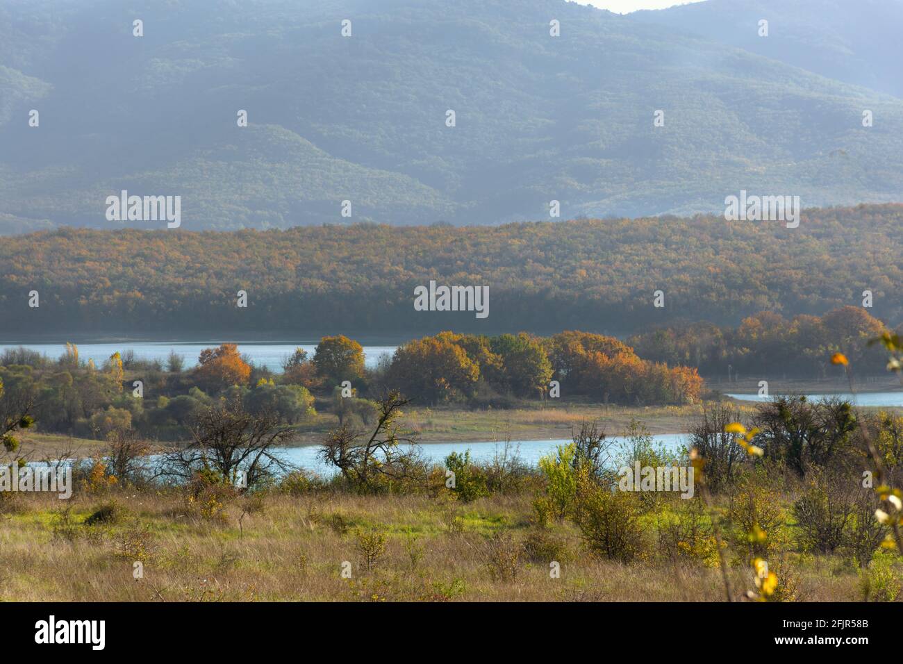 Autumn mountains forest lake. Golden autumn landscape with a blue lake. Colorful orange-red trees in a light misty haze. The concept of warm autumn we Stock Photo