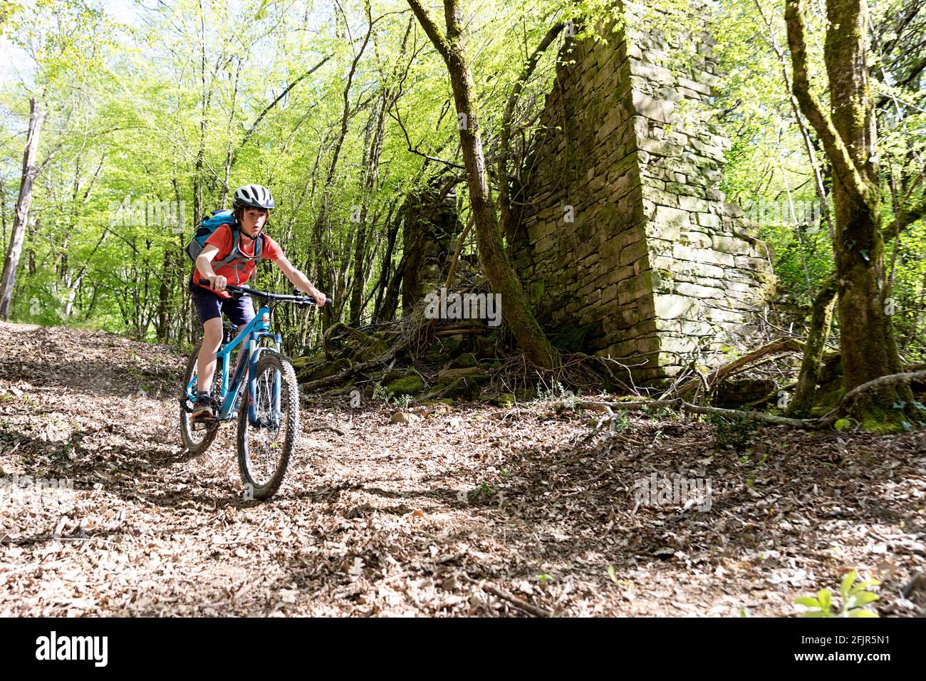 young boy is riding with the dirtbike in the spring landscape downhill Stock Photo