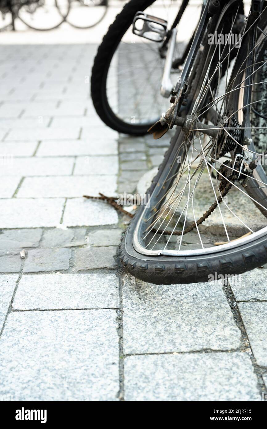 The bent rear tire of a bicycle in the city with destroyed chain. Stock Photo