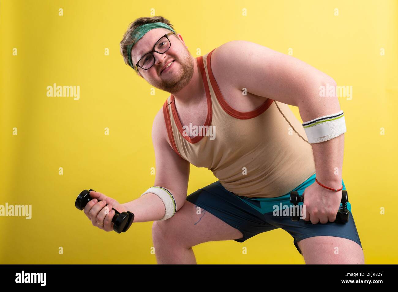 fat man wearing black shirt exercising with dumbbells and looking at camera Stock Photo