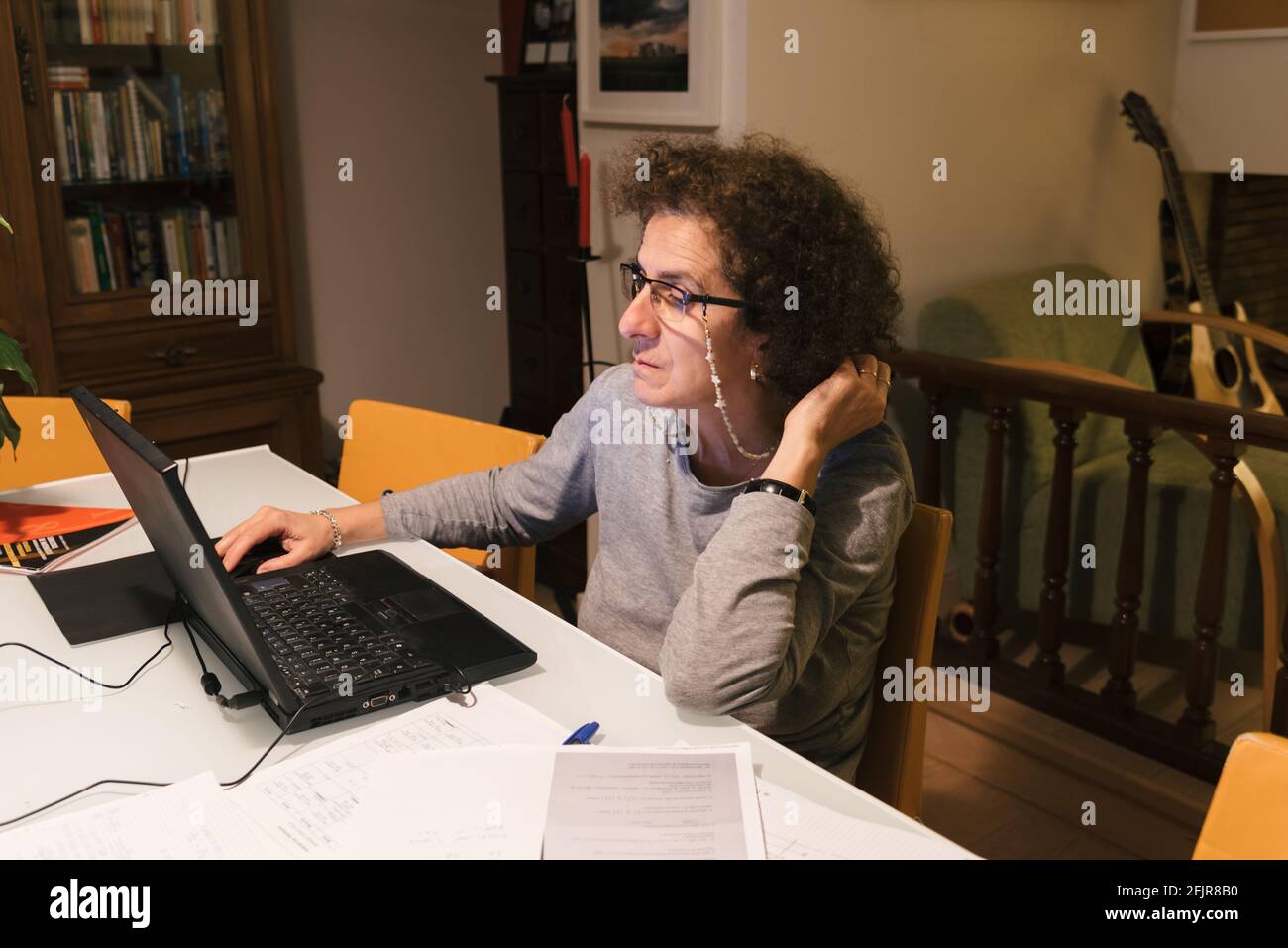Businesswoman wearing glasses working on laptop computer sitting at home and managing her business. Home office concept during Coronavirus Stock Photo
