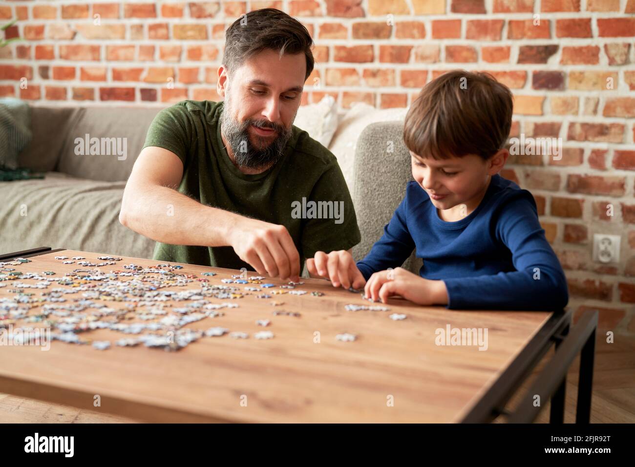 Boy solving jigsaw puzzle with father in living room at home Stock Photo