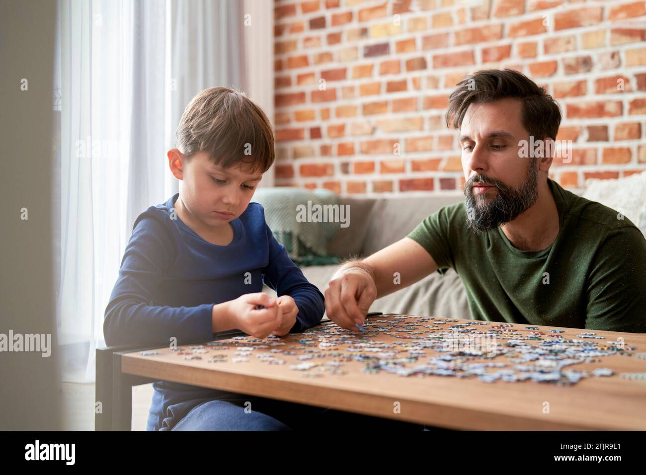 Father and son solving jigsaw puzzle together at home Stock Photo
