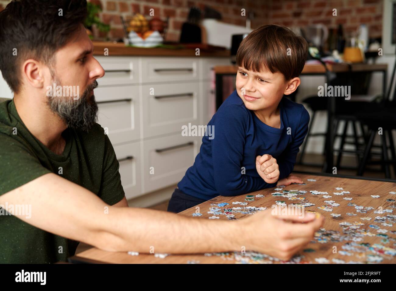 Father and son sitting and solving jigsaw puzzle Stock Photo