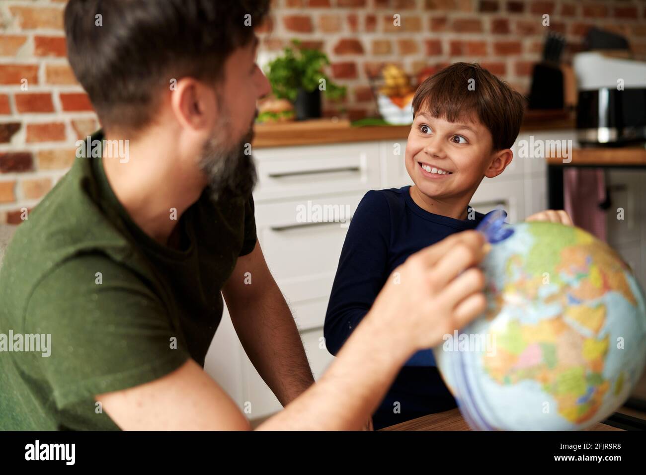 Happy father and son looking at globe of the world Stock Photo
