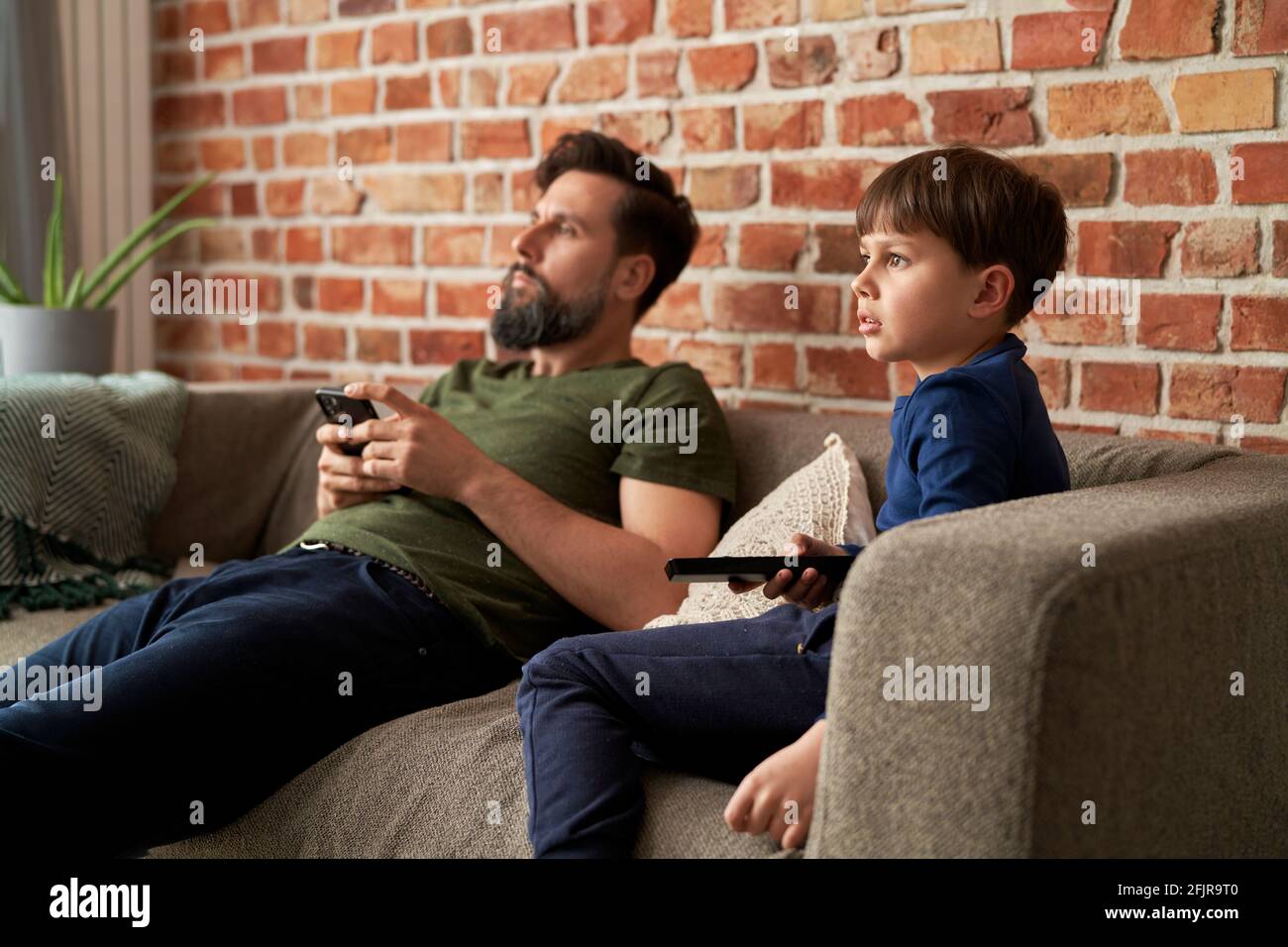 Father and son watches TV together at home Stock Photo