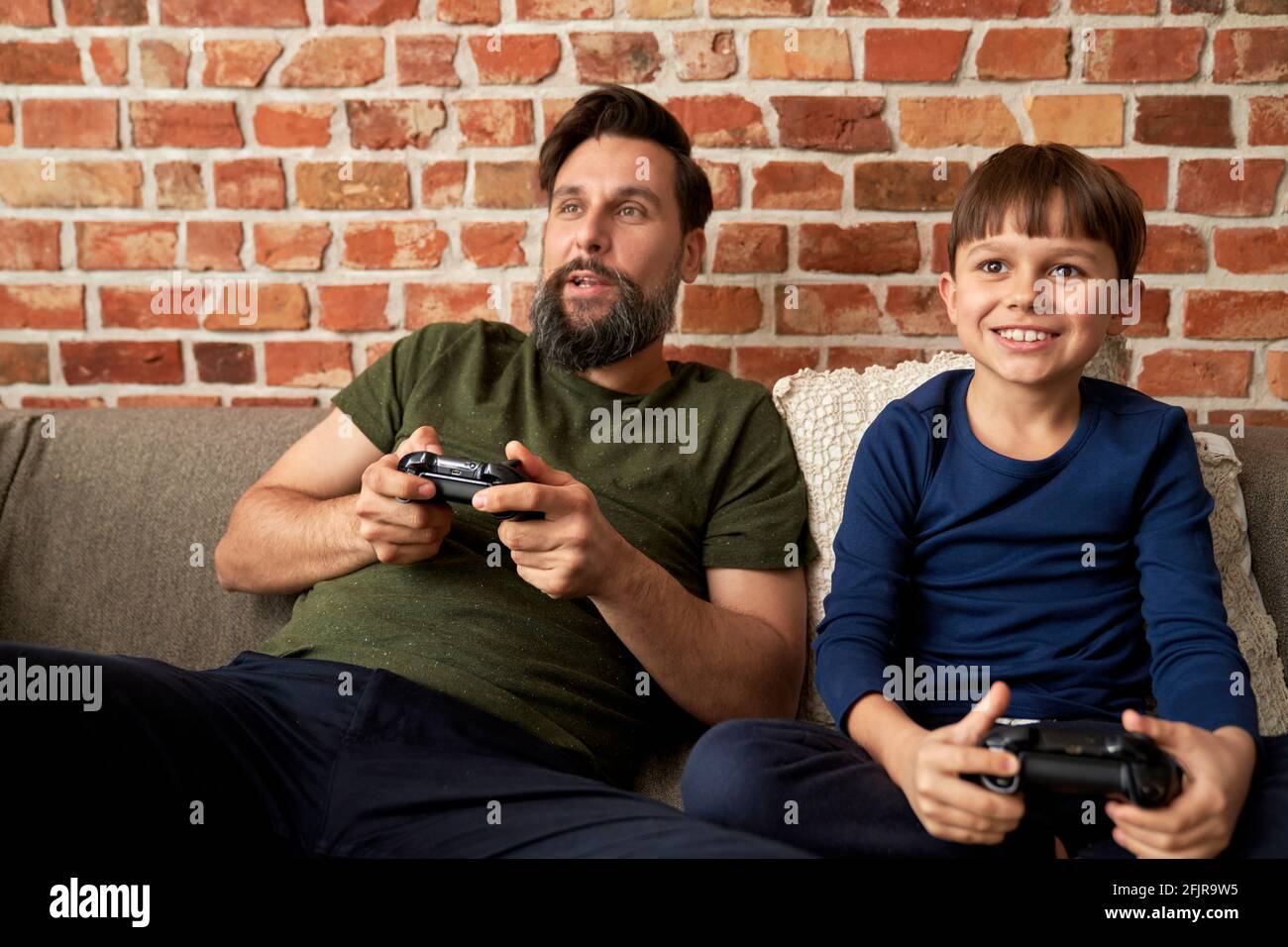 Happy father and son playing video game on couch Stock Photo