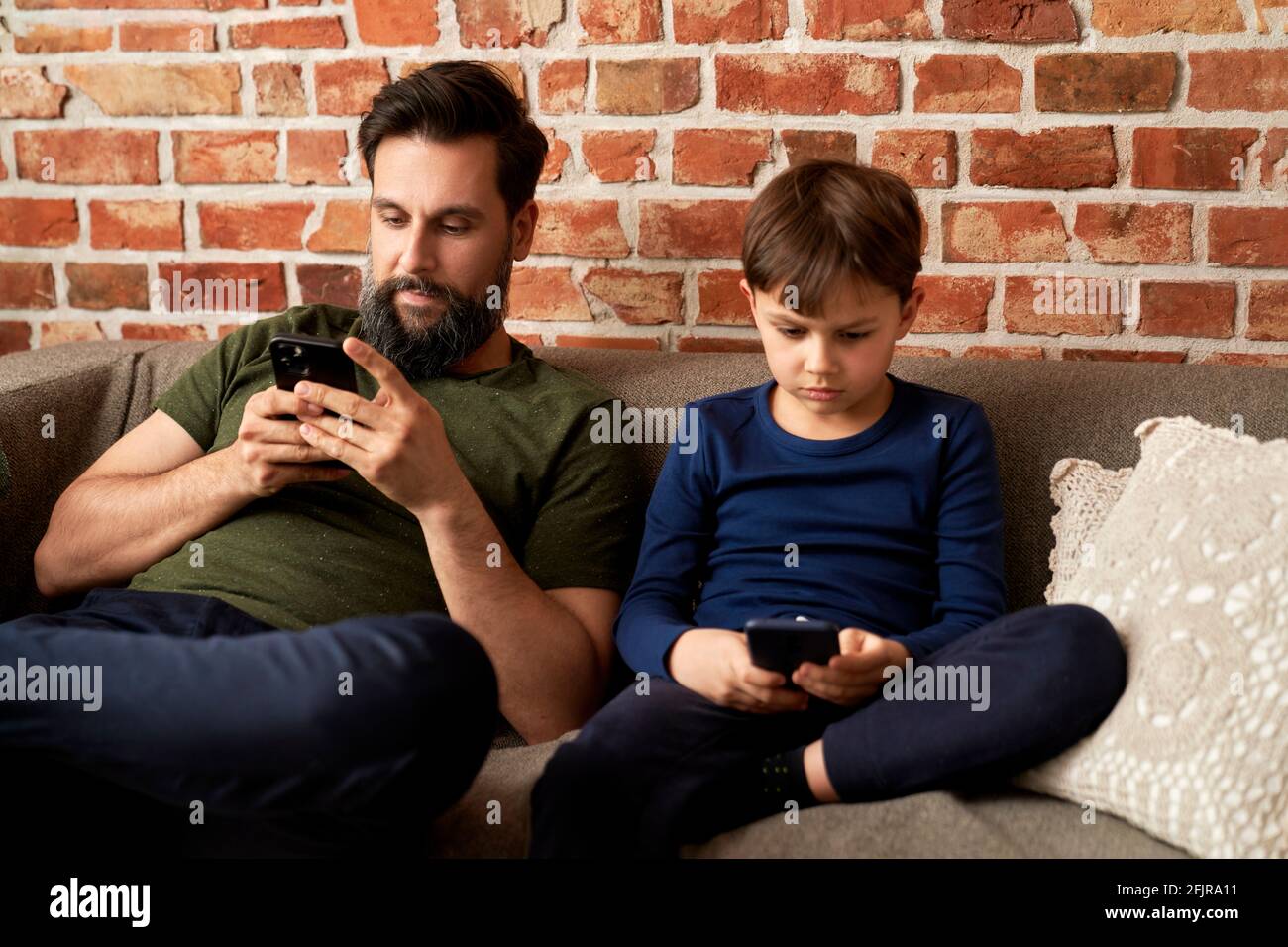 Father and son spending time with mobile phone at home Stock Photo