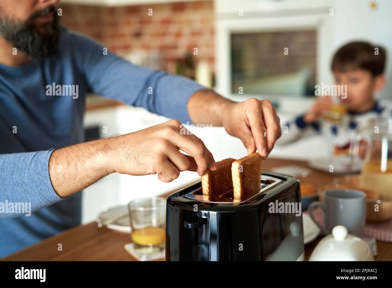 Close up of man pulling toast from a toaster Stock Photo
