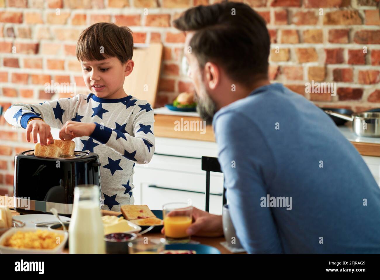 Son helps to prepare breakfast for himself and father Stock Photo