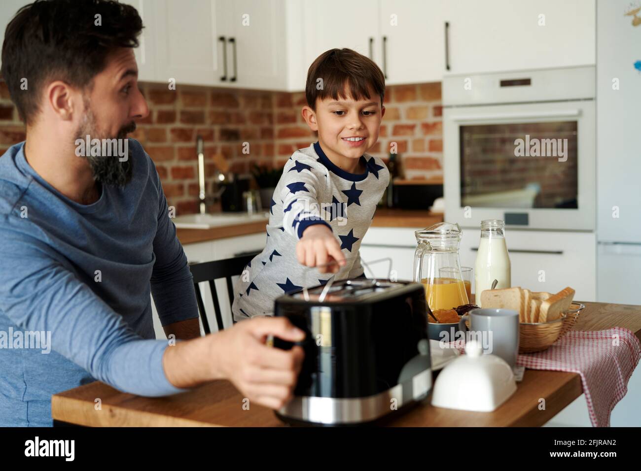 Smiling boy waiting for toasts from a toaster Stock Photo