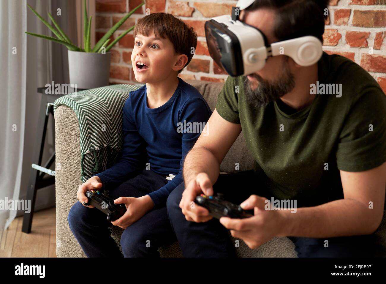 Father wearing VR glasses playing with son at home Stock Photo