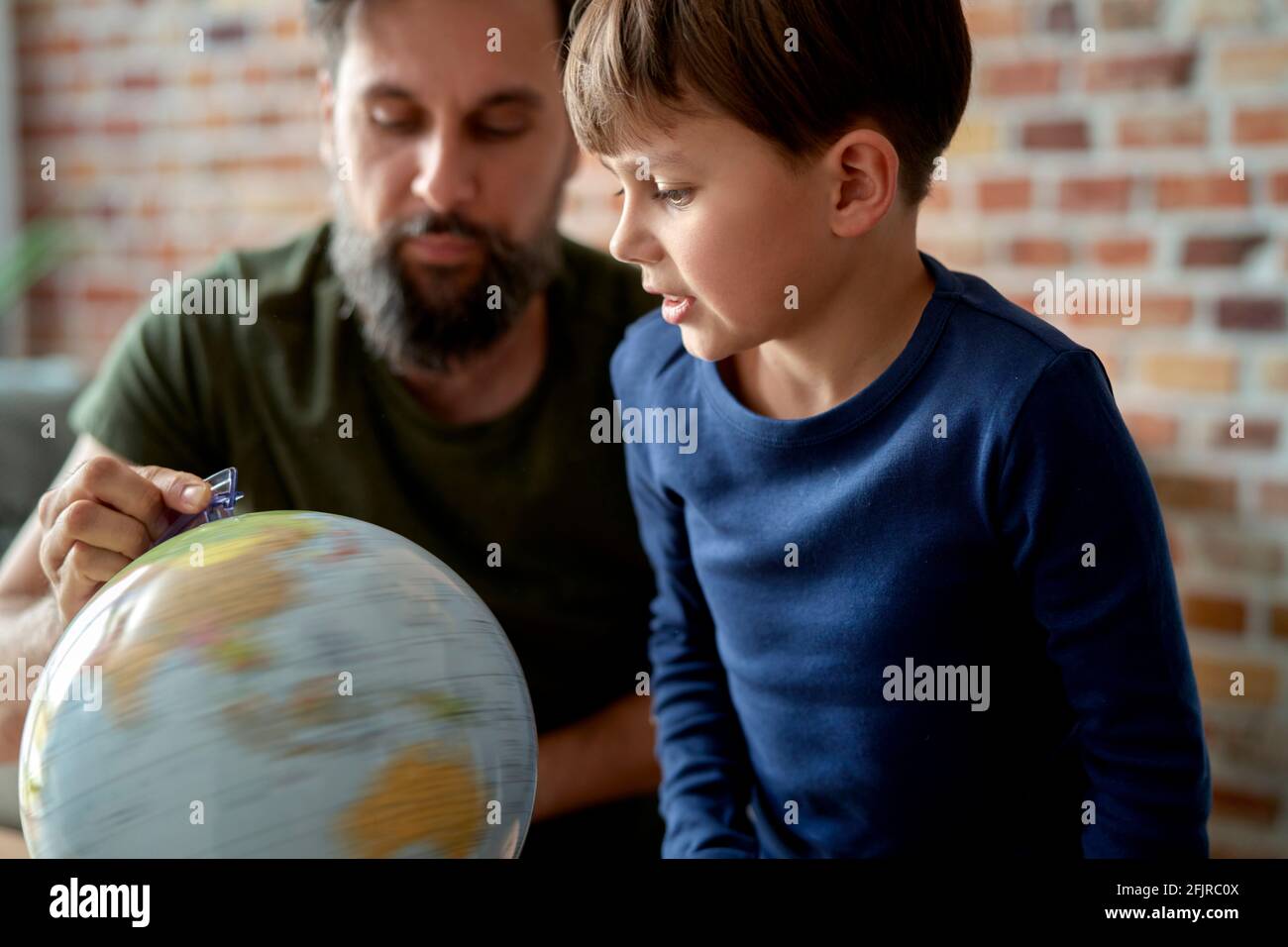 Son and father looking at spinning globe Stock Photo