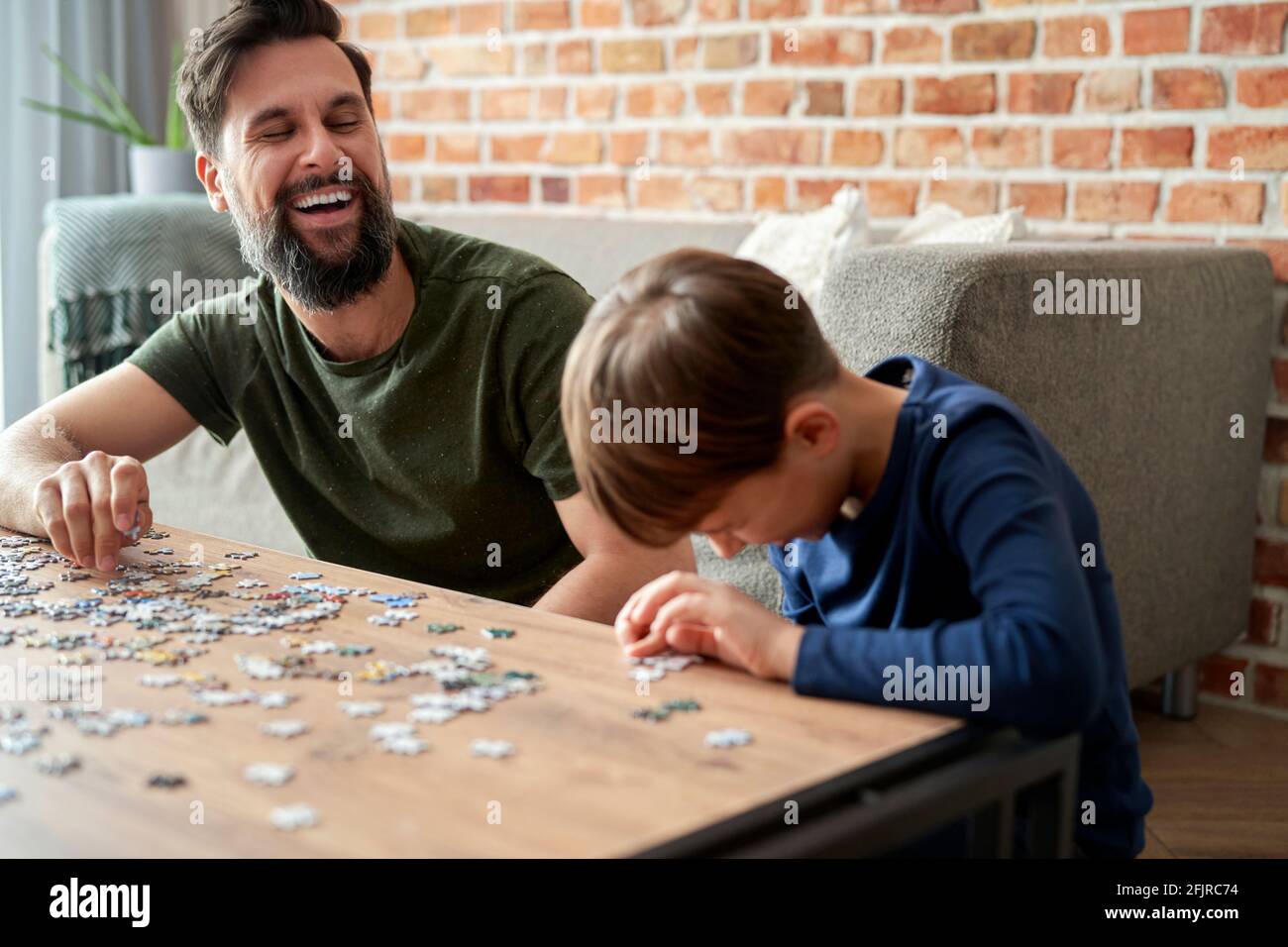 Happy son and father having fun during solving jigsaw puzzle Stock Photo