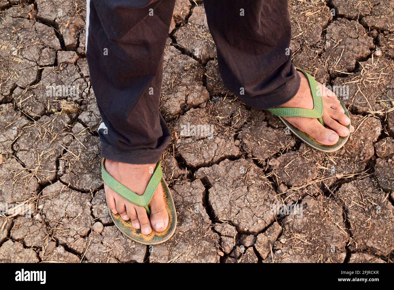Male feet with slippers on dry earth. Water scarcity concept Stock Photo