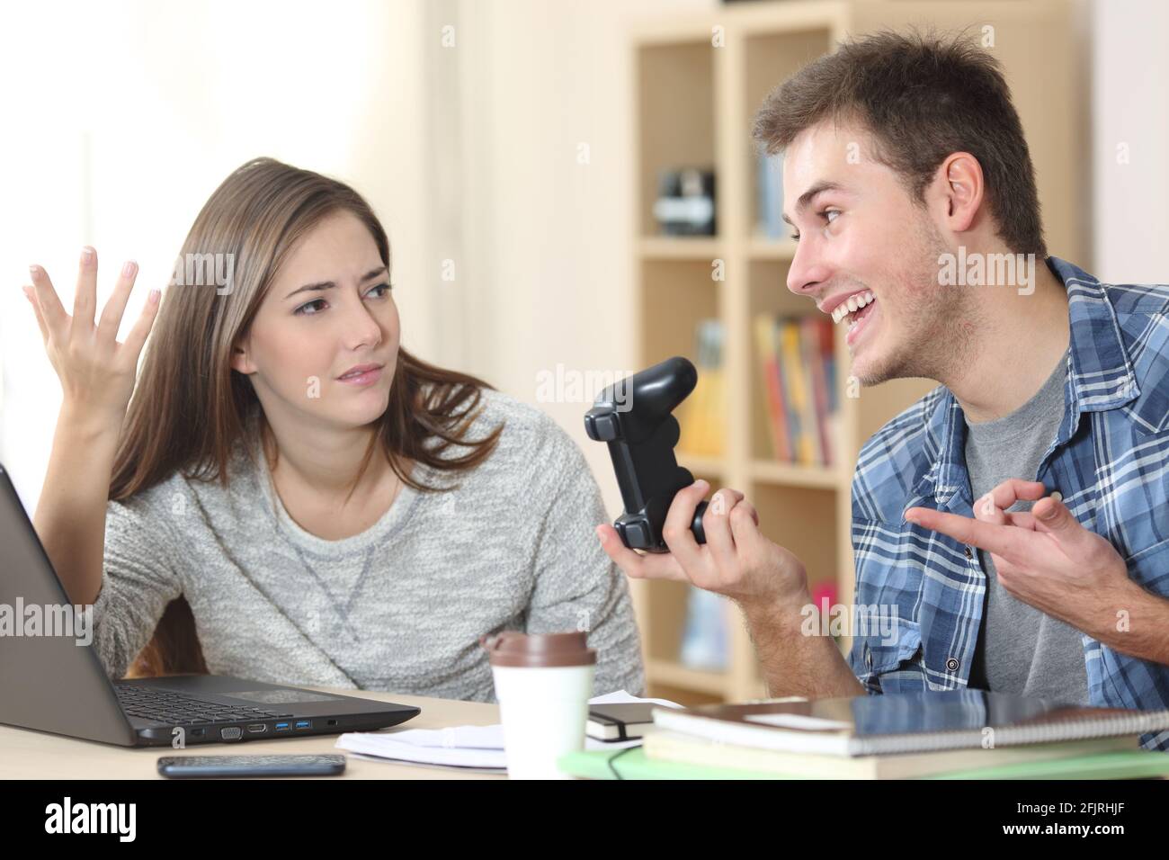 Angry student girl complaining to lazy classmate waiting to do homework at home Stock Photo