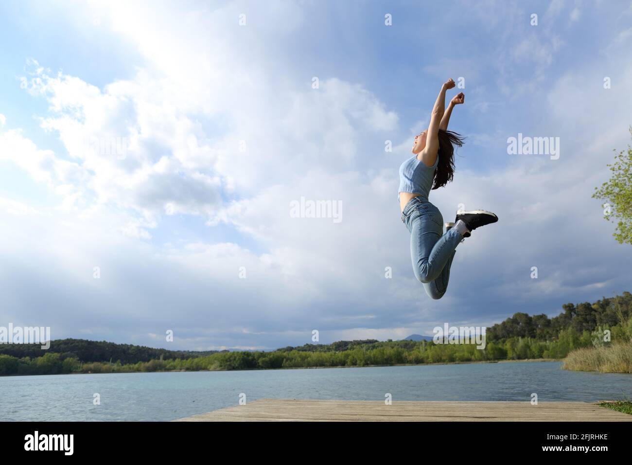 Profile of a happy woman jumping in a lake celebrating Stock Photo